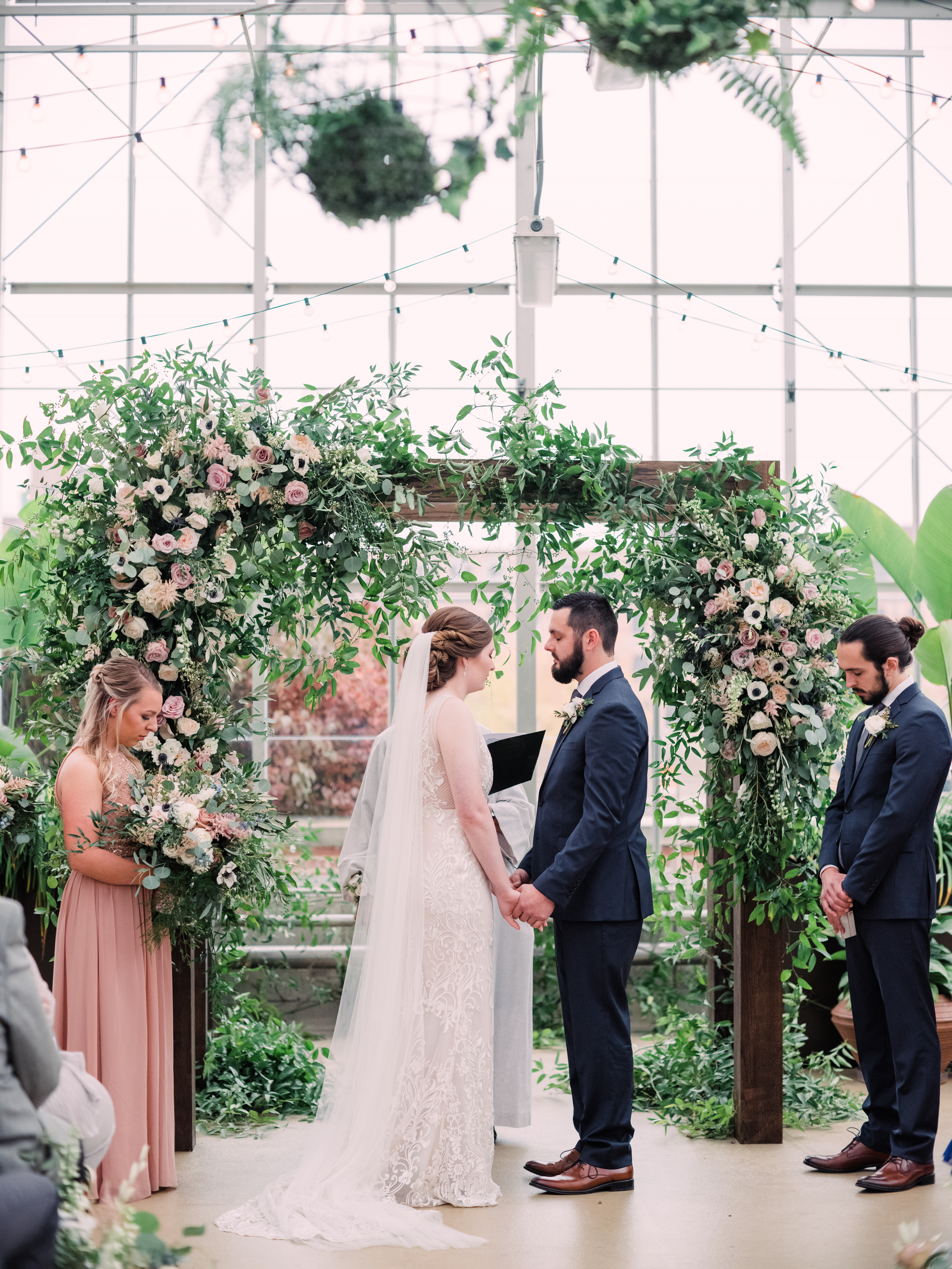 Bride and groom in front of floral arbor backdrop