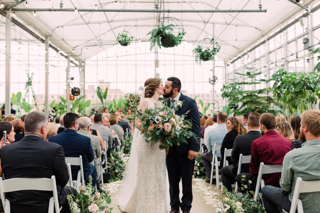 Just married couple kissing after greenhouse ceremony