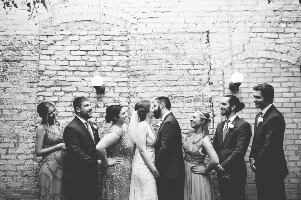Bridal party photos in front of brick wall