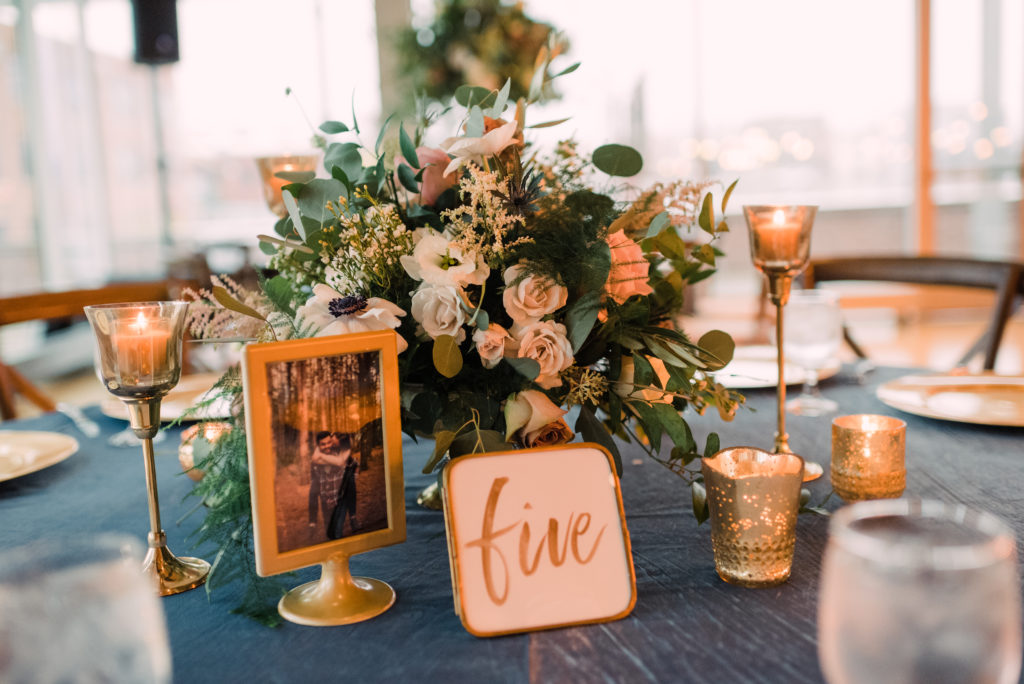 Floral centerpiece with gold table number and picture frame