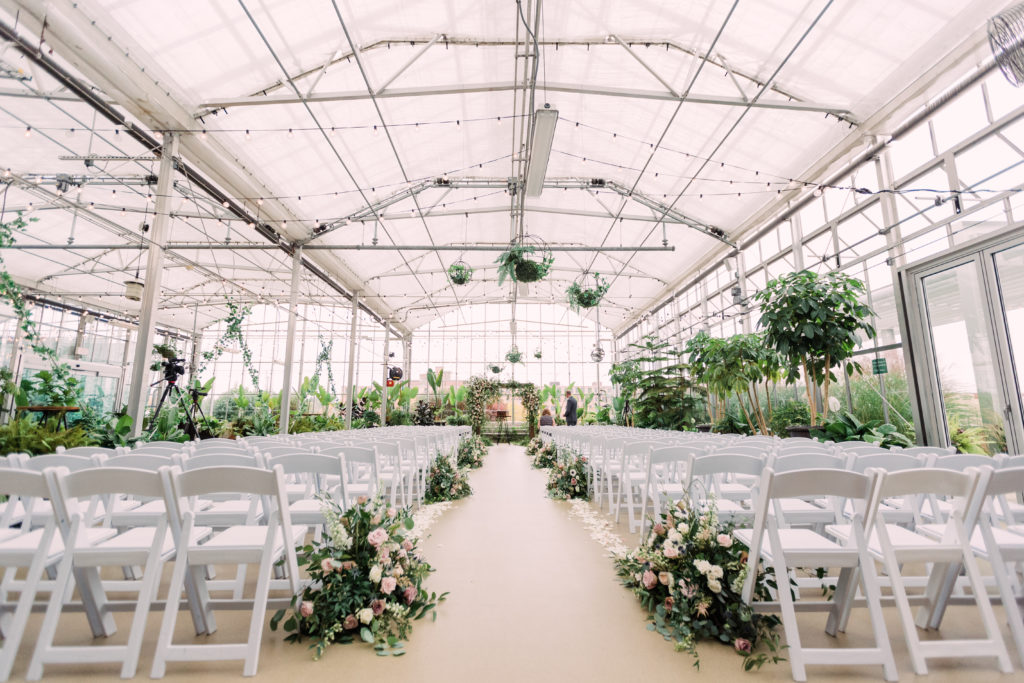 Greenhouse ceremony cite with large floral aisle accents